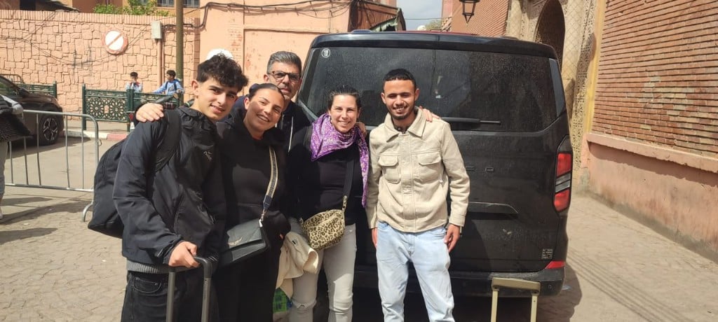 Guests and their El Farissi Journey guide smiling together by the tour van in Morocco